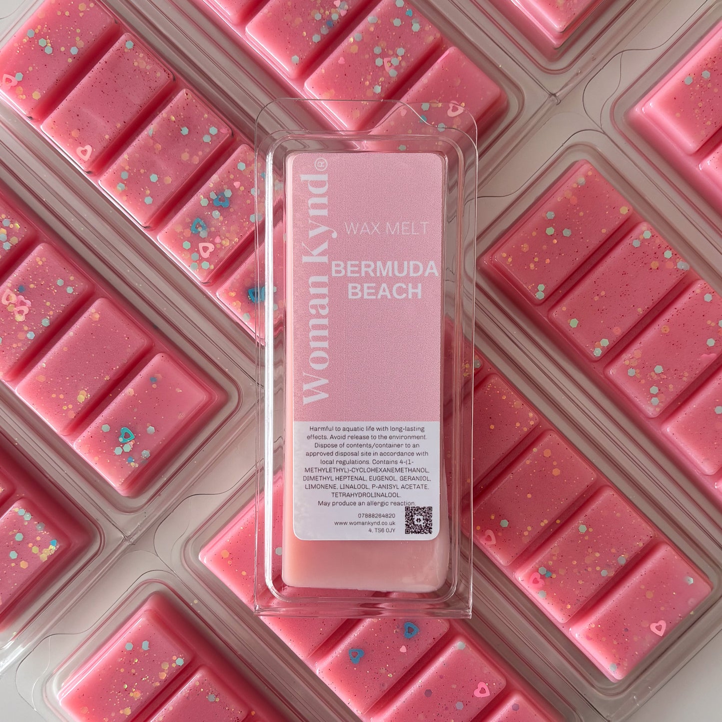 A package of pink wax tarts with a clear section revealing a white label with 'Bermuda Beach' written on it, along with the Womanly brand logo.