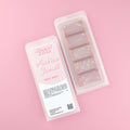 Two images of a Woman Kynd five segment light brown Wax Melt with gold glitter, both in a frosted clamshell. The first image displays the pink and white label with the words Woman Kynd Arabian Sunset Wax Melt and the CLP information, and the other image is of the reverse side showing the Wax Melt Itself. Both images are against a solid pink background.