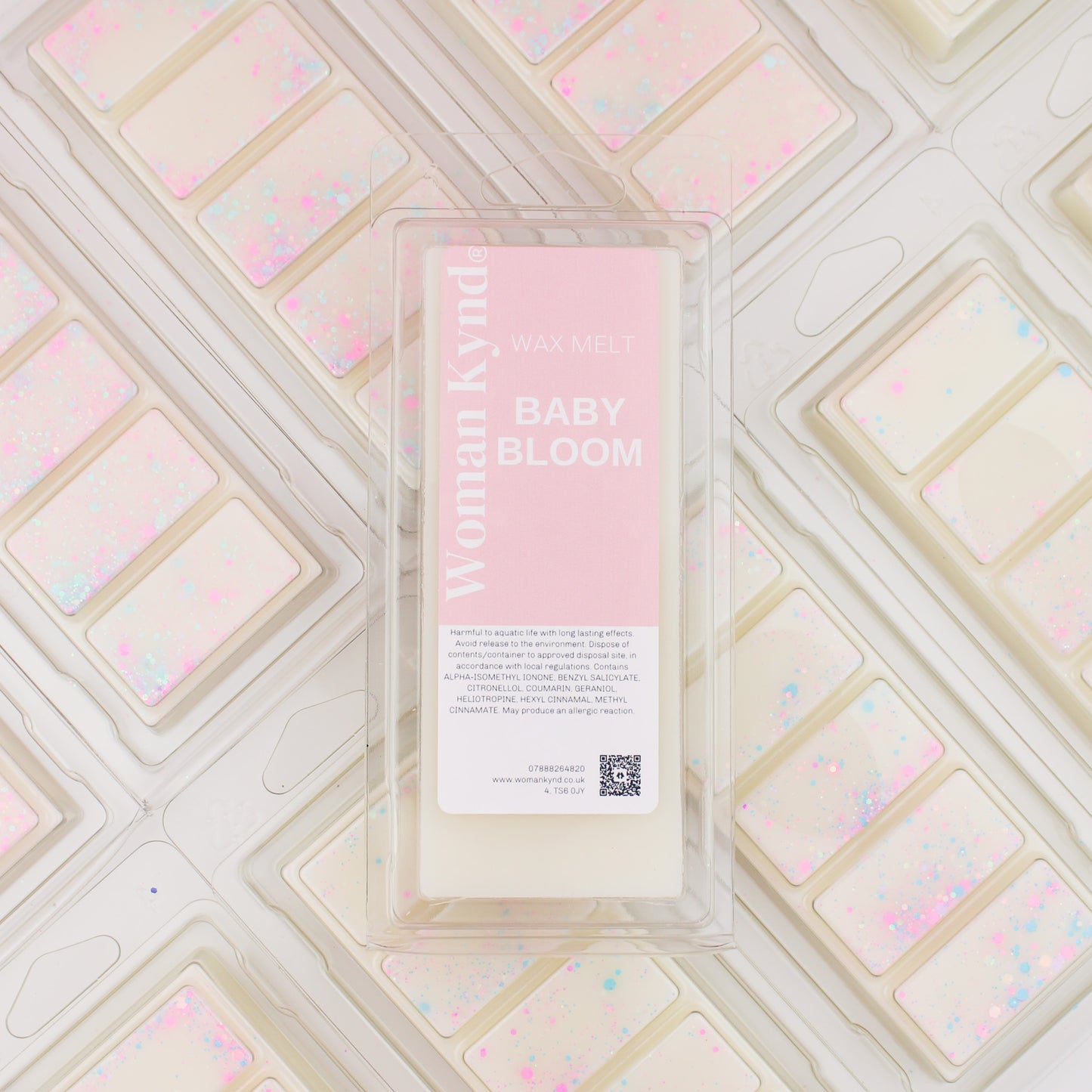 A wax melt pack labeled 'Baby Bloom' with a pink and white color scheme, placed on a similar patterned background.
