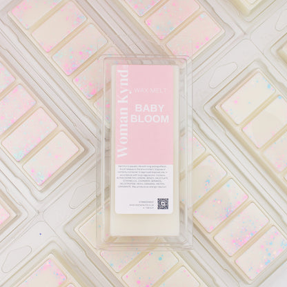 A wax melt pack labeled 'Baby Bloom' with a pink and white color scheme, placed on a similar patterned background.