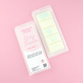 Two images of a Woman Kynd five segment white Wax Melt with light blue glitter, both in a frosted clamshell. The first image displays the pink and white label with the words Woman Kynd Baby Powder Wax Melt and the CLP information, and the other image is of the reverse side showing the Wax Melt Itself. Both images are against a solid pink background.
