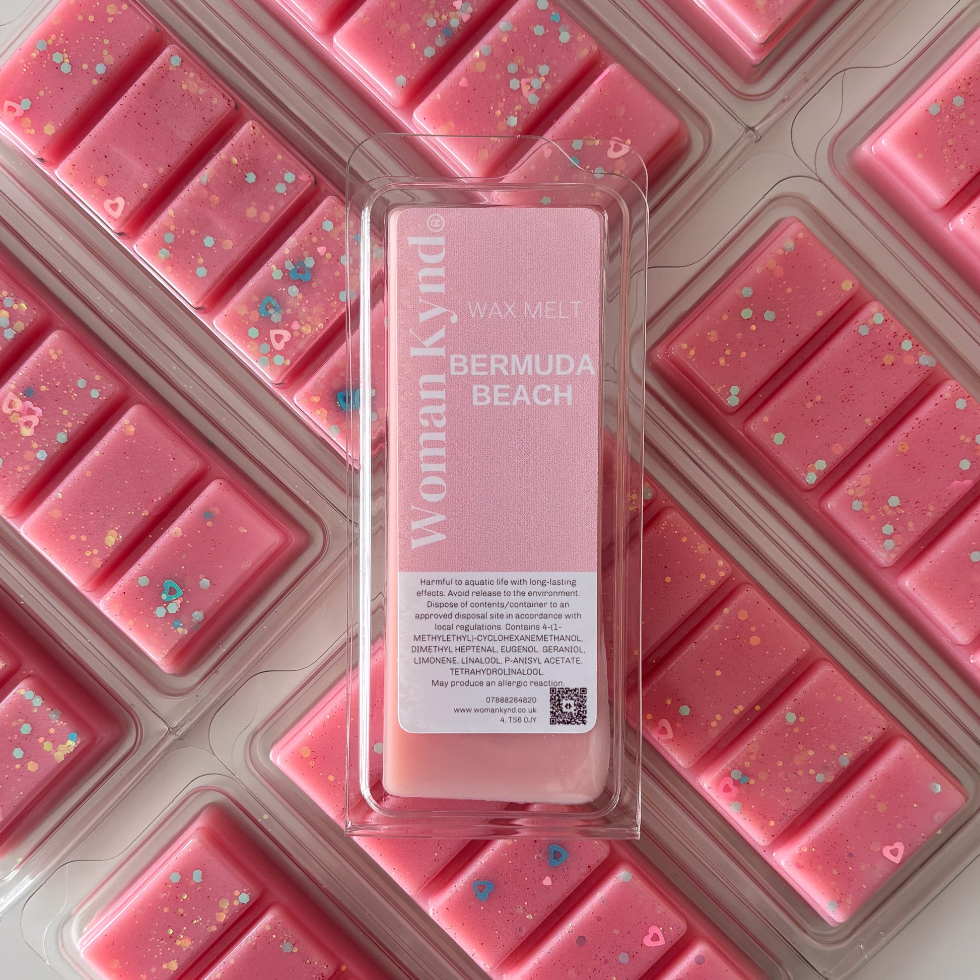 A package of pink wax tarts with a clear section revealing a white label with 'Bermuda Beach' written on it, along with the Womanly brand logo.