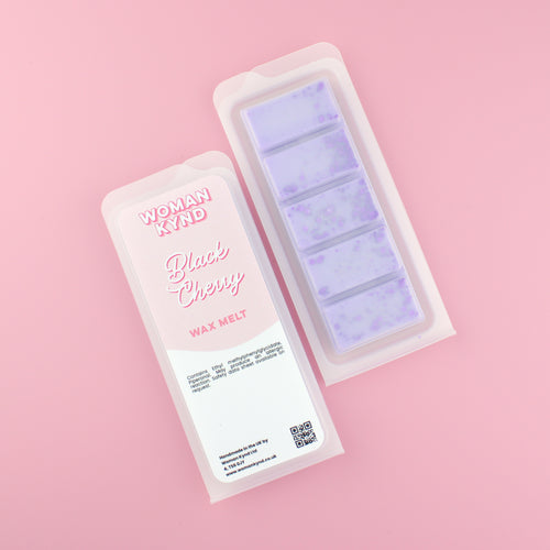 Two images of a Woman Kynd five segment light purple Wax Melt with dark purple glitter, both in a frosted clamshell. The first image displays the pink and white label with the words Woman Kynd Black Cherry Wax Melt and the CLP information, and the other image is of the reverse side showing the Wax Melt Itself. Both images are against a solid pink background.