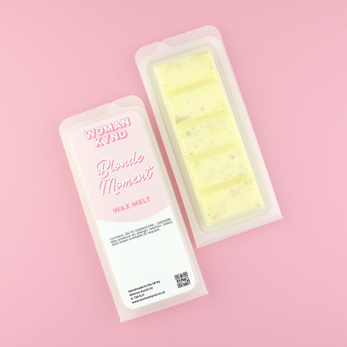 Two images of a Woman Kynd five segment beige Wax Melt with gold glitter, both in a frosted clamshell. The first image displays the pink and white label with the words Woman Kynd Blonde Moment Wax Melt and the CLP information, and the other image is of the reverse side showing the Wax Melt Itself. Both images are against a solid pink background.