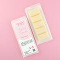 Two images of a Woman Kynd five segment pale yellow Wax Melt with gold glitter, both in a frosted clamshell. The first image displays the pink and white label with the words Woman Kynd Dubai Dunes Wax Melt and the CLP information, and the other image is of the reverse side showing the Wax Melt Itself. Both images are against a solid pink background.