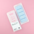 Two images of a Woman Kynd five segment light blue Wax Melt with white glitter, both in a frosted clamshell. The first image displays the pink and white label with the words Woman Kynd Fresh Quilt Wax Melt and the CLP information, and the other image is of the reverse side showing the Wax Melt Itself. Both images are against a solid pink background.