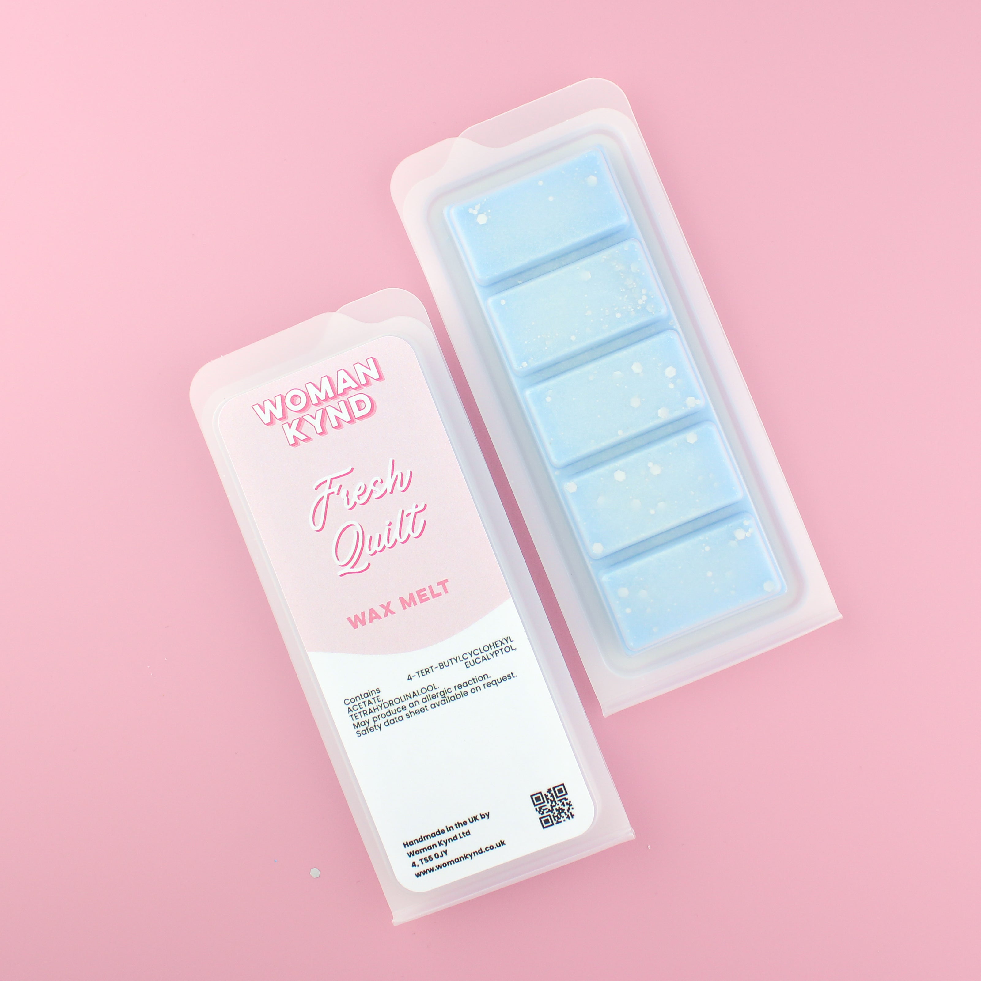 Two images of a Woman Kynd five segment light blue Wax Melt with white glitter, both in a frosted clamshell. The first image displays the pink and white label with the words Woman Kynd Fresh Quilt Wax Melt and the CLP information, and the other image is of the reverse side showing the Wax Melt Itself. Both images are against a solid pink background.