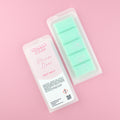 Two images of a Woman Kynd five segment light green Wax Melt with white glitter, both in a frosted clamshell. The first image displays the pink and white label with the words Woman Kynd Hoover Lines Wax Melt and the CLP information, and the other image is of the reverse side showing the Wax Melt Itself. Both images are against a solid pink background.
