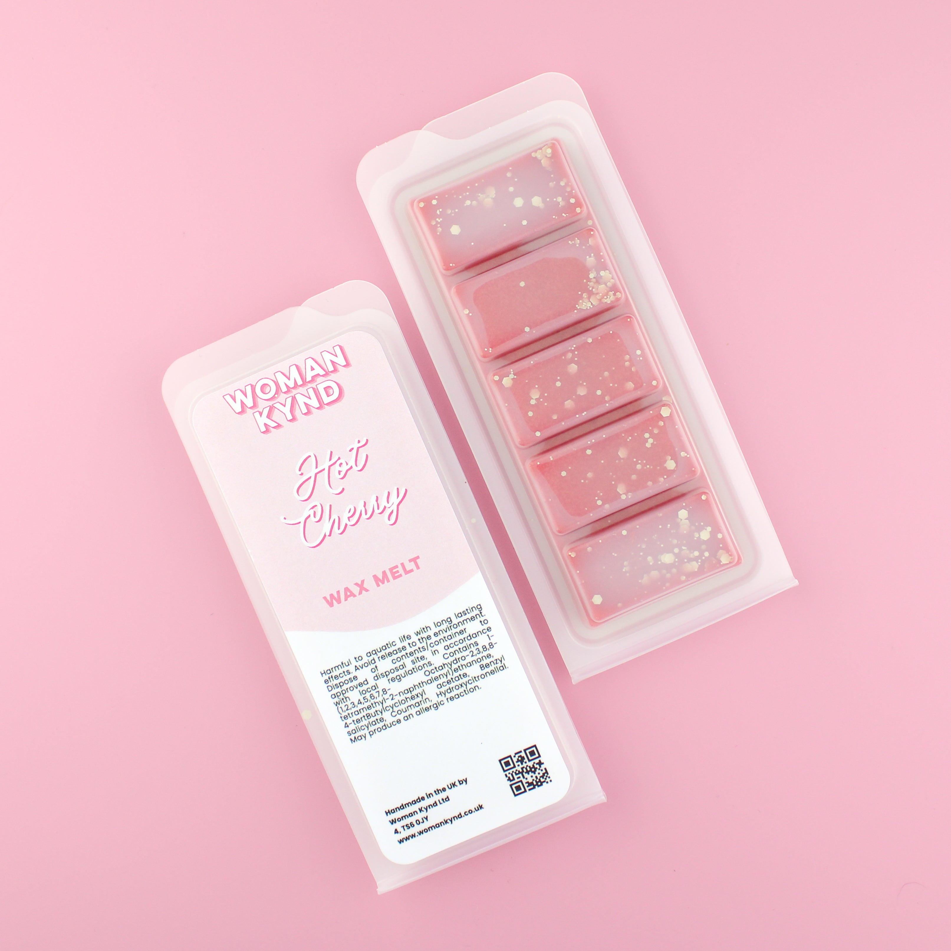 Two images of a Woman Kynd five segment red Wax Melt with gold glitter, both in a frosted clamshell. The first image displays the pink and white label with the words Woman Kynd Hot Cherry Wax Melt and the CLP information, and the other image is of the reverse side showing the Wax Melt Itself. Both images are against a solid pink background.