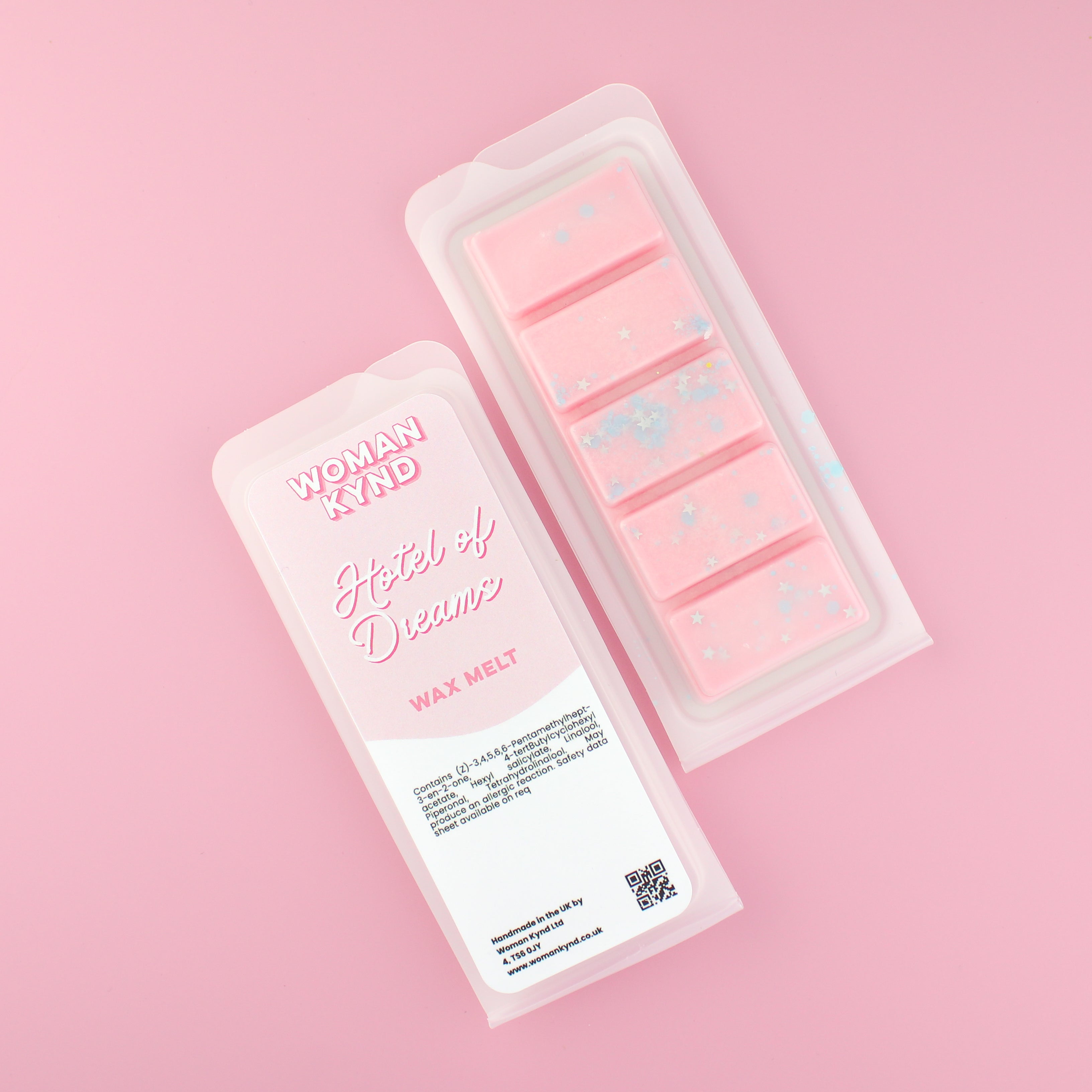 Two images of a Woman Kynd five segment pink Wax Melt with blue and silver shaped glitter, both in a frosted clamshell. The first image displays the pink and white label with the words Woman Kynd Hotel Of Dreams Wax Melt and the CLP information, and the other image is of the reverse side showing the Wax Melt Itself. Both images are against a solid pink background.