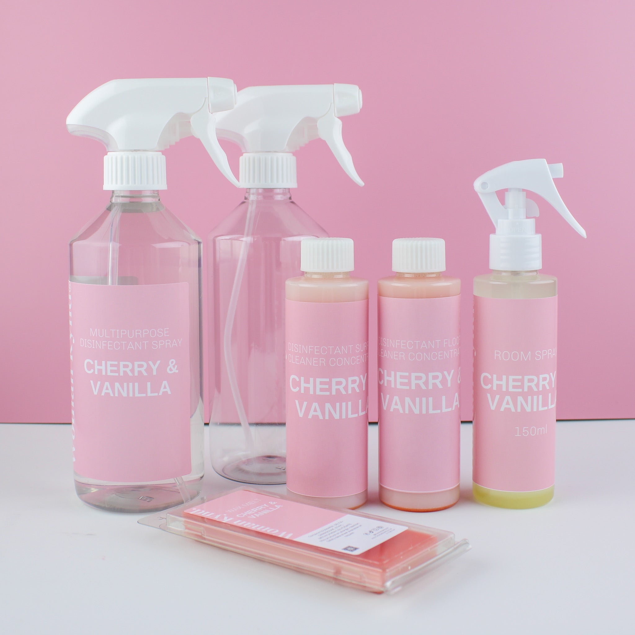 Set of Cherry & Vanilla products including bottles and cloths on a pink background