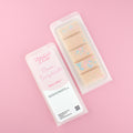 Two images of a Woman Kynd five segment beige Wax Melt with pink and blue glitter, both in a frosted clamshell. The first image displays the pink and white label with the words Woman Kynd Mmm...Doughnuts Wax Melt and the CLP information, and the other image is of the reverse side showing the Wax Melt Itself. Both images are against a solid pink background.
