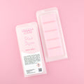 Two images of a Woman Kynd five segment light pink Wax Melt with white glitter, both in a frosted clamshell. The first image displays the pink and white label with the words Woman Kynd Pink Sugar Wax Melt and the CLP information, and the other image is of the reverse side showing the Wax Melt Itself. Both images are against a solid pink background.