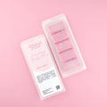 Two images of a Woman Kynd five segment pink Wax Melt with light pink glitter, both in a frosted clamshell. The first image displays the pink and white label with the words Woman Kynd Raspberry Candy Floss Wax Melt and the CLP information, and the other image is of the reverse side showing the Wax Melt Itself. Both images are against a solid pink background.
