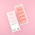 Two images of a Woman Kynd five segment red Wax Melt with yellow glitter, both in a frosted clamshell. The first image displays the pink and white label with the words Woman Kynd Rhubarb & Custard Wax Melt and the CLP information, and the other image is of the reverse side showing the Wax Melt Itself. Both images are against a solid pink background.