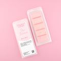 Two images of a Woman Kynd five segment light pink Wax Melt with gold glitter, both in a frosted clamshell. The first image displays the pink and white label with the words Woman Kynd Rio Sunrise Wax Melt and the CLP information, and the other image is of the reverse side showing the Wax Melt Itself. Both images are against a solid pink background.