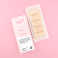Two images of a Woman Kynd five segment beige Wax Melt with gold glitter, both in a frosted clamshell. The first image displays the pink and white label with the words Woman Kynd Show Home Wax Melt and the CLP information, and the other image is of the reverse side showing the Wax Melt Itself. Both images are against a solid pink background.