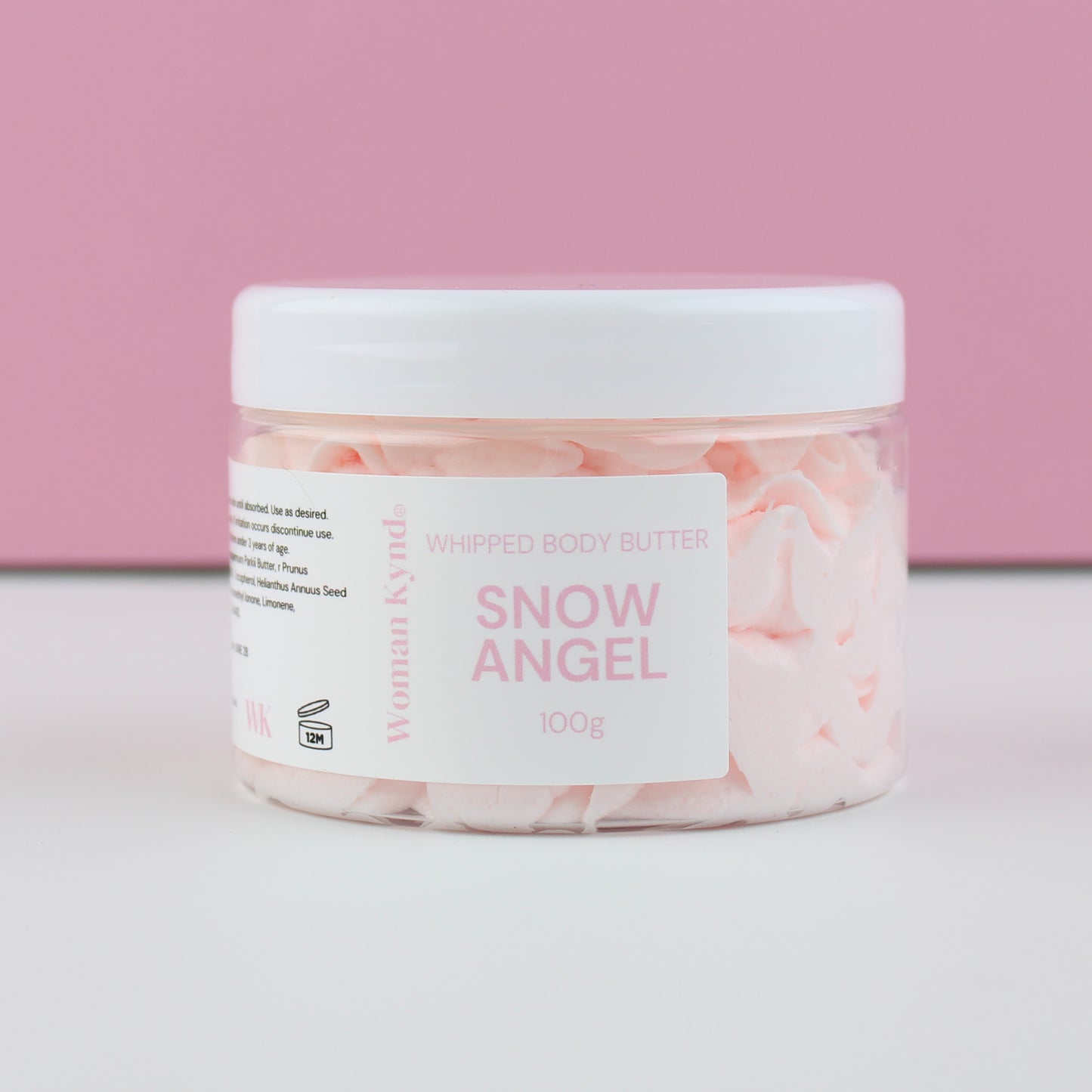 Jar of 'Snow Angel' whipped body butter with a pink and white label on a light pink background