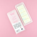 Two images of a Woman Kynd five segment white Wax Melt with pale blue glitter, both in a frosted clamshell. The first image displays the pink and white label with the words Woman Kynd Soft Touch Wax Melt and the CLP information, and the other image is of the reverse side showing the Wax Melt Itself. Both images are against a solid pink background.