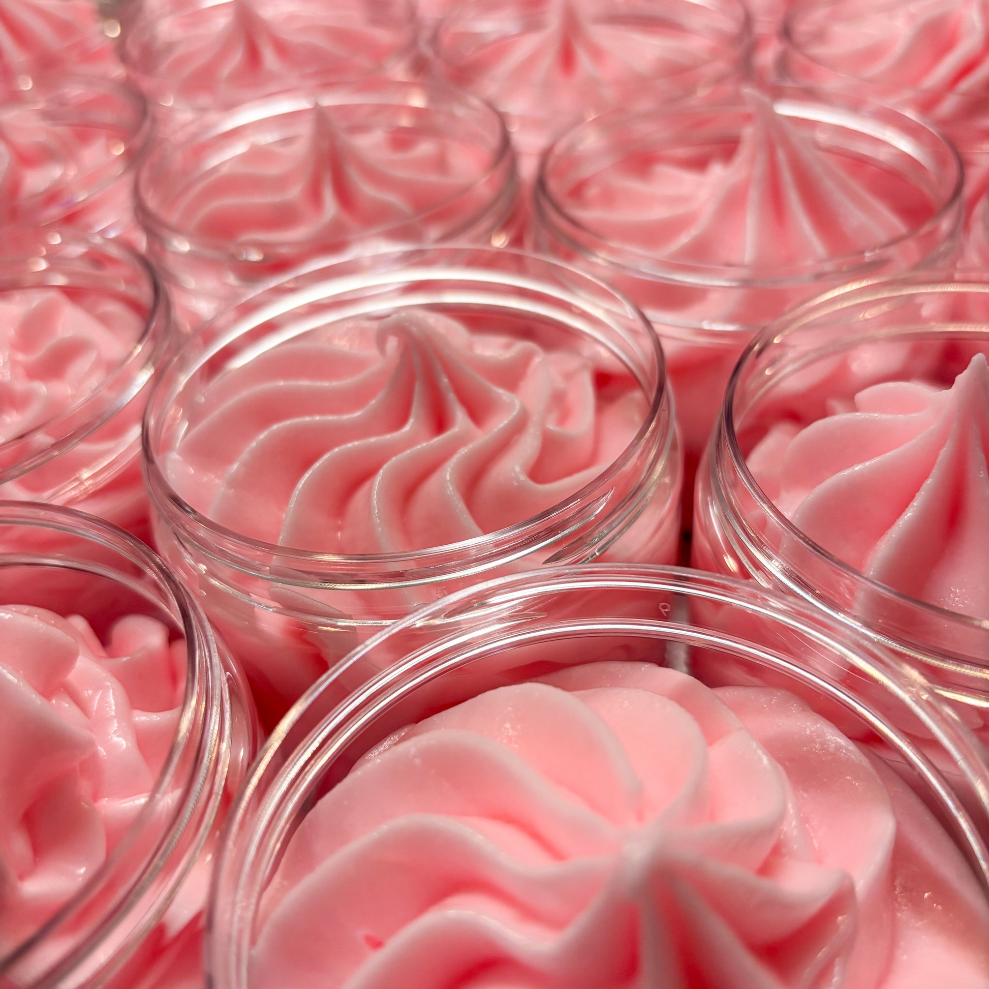 Clear plastic containers filled with pink whipped body butter